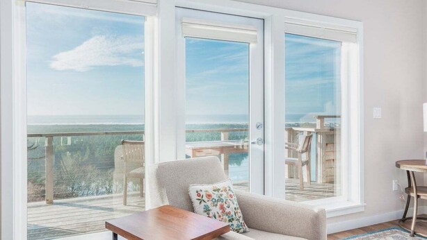 Una habitación con un amplio ventanal corredero que da a un balcón con vistas al océano.