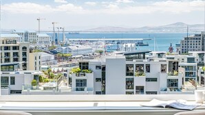 Een moderne hotelkamer met uitzicht op een jachthaven en stadsgezicht.