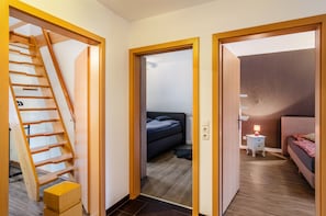 A staircase leading to a bedroom with a bed, bedside table, and lamp. - Holiday Home 'Haus Mit Garten Und Kamin' with Terrace, Private Garden and Wi-Fi (Wilhelmshaven)