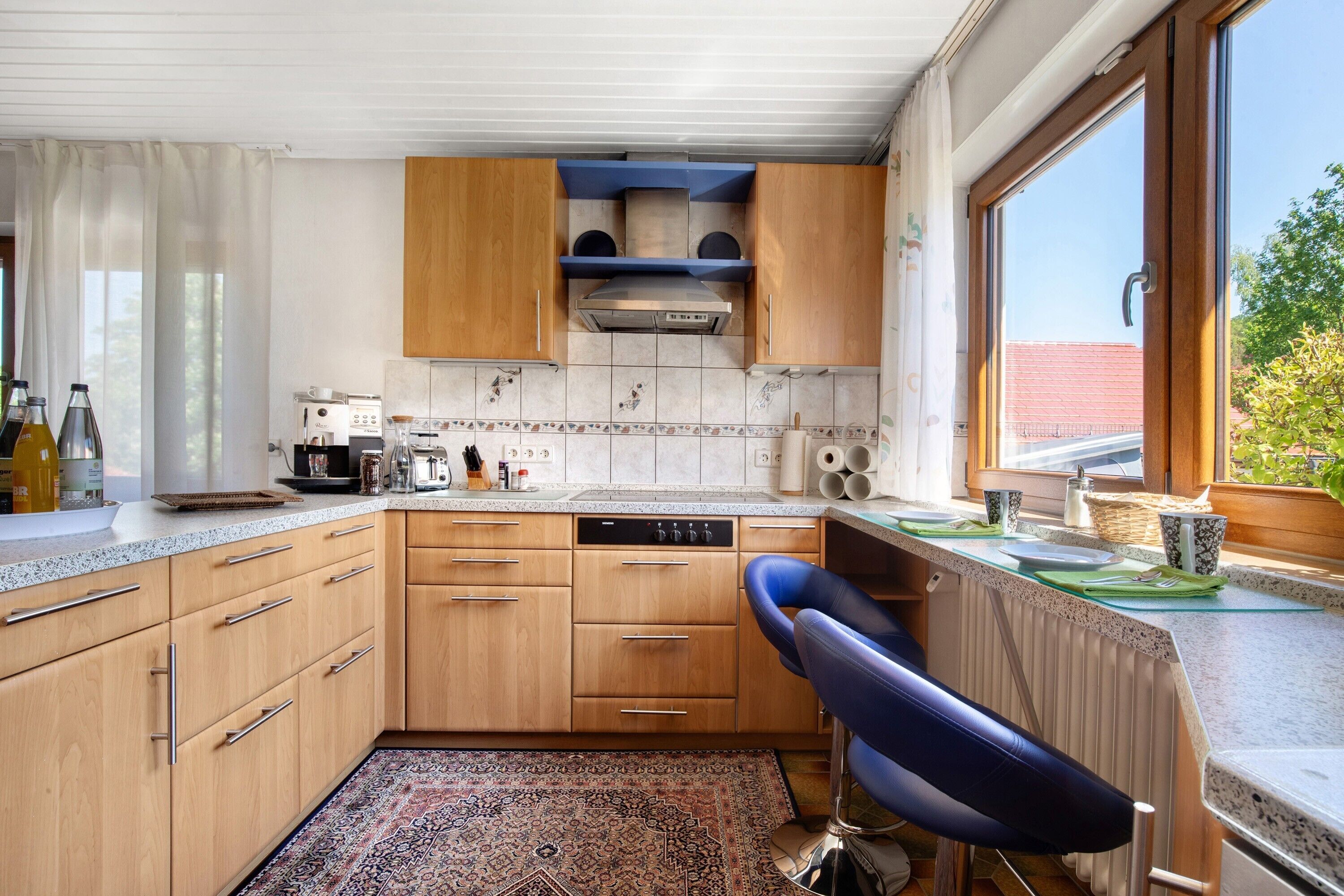 A kitchen with wooden cabinets, a dishwasher, and a window with a view of a building and trees.