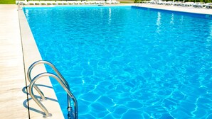 A clear blue swimming pool with a metal ladder on the left side. - Bella Ella Hotel (Kasoa)