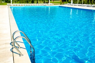 A clear blue swimming pool with a metal ladder on the left side.