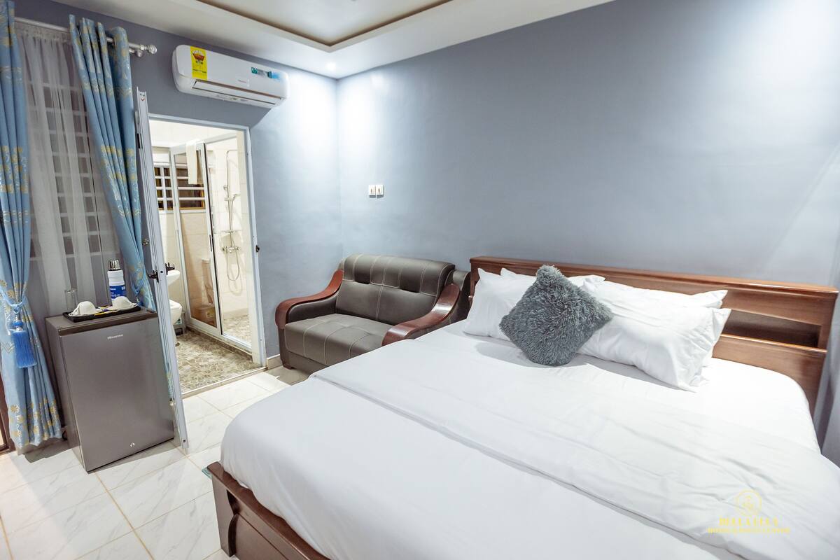 Ein Hotelzimmer mit Bett, kleinem Schreibtisch, Stuhl und Klimaanlage.