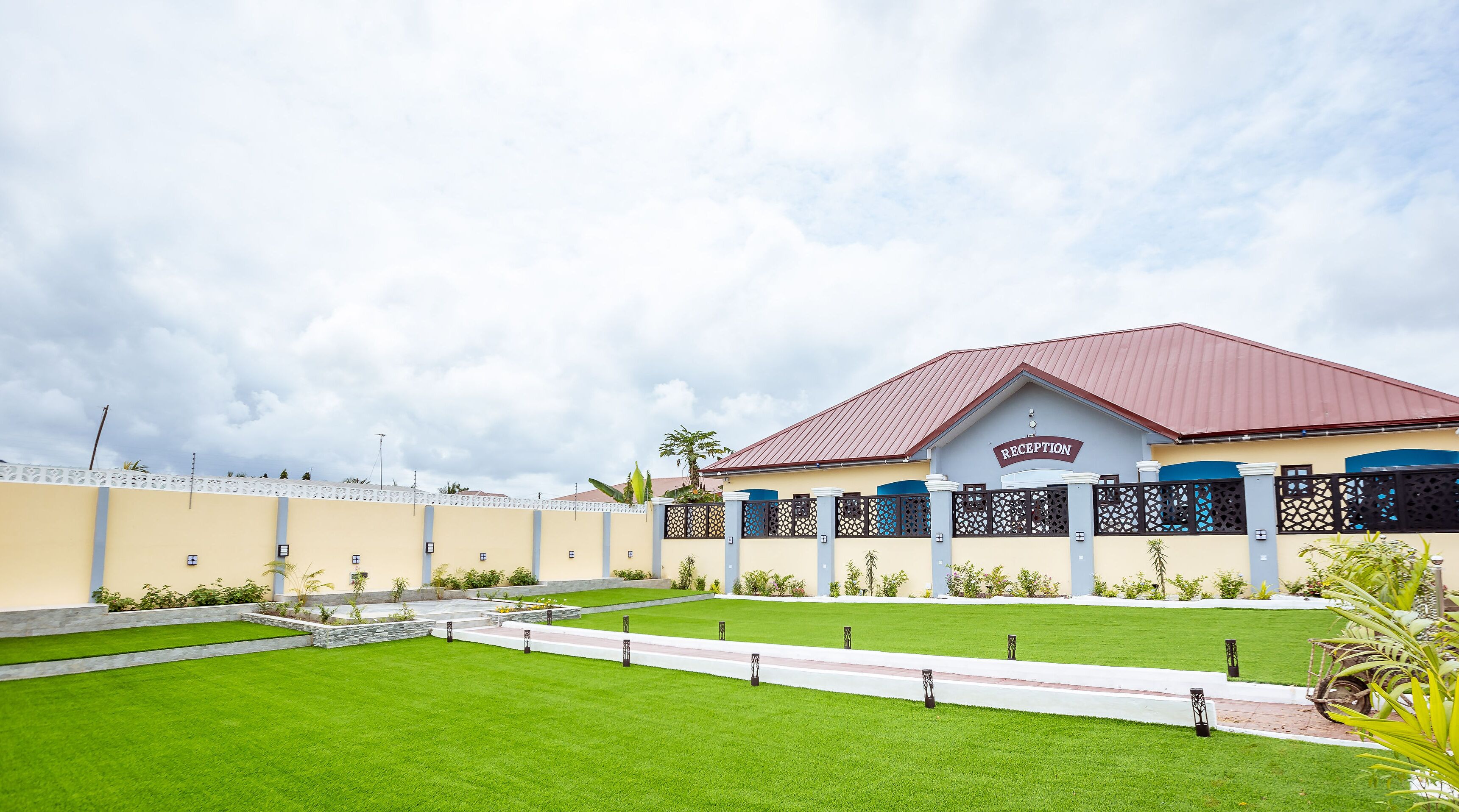 A reception building with a red roof, beige walls, and a sign that reads "RECEPTION".