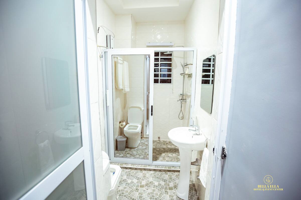 Ein Badezimmer mit Glasduschtür, Toilette, Waschbecken und Spiegel.