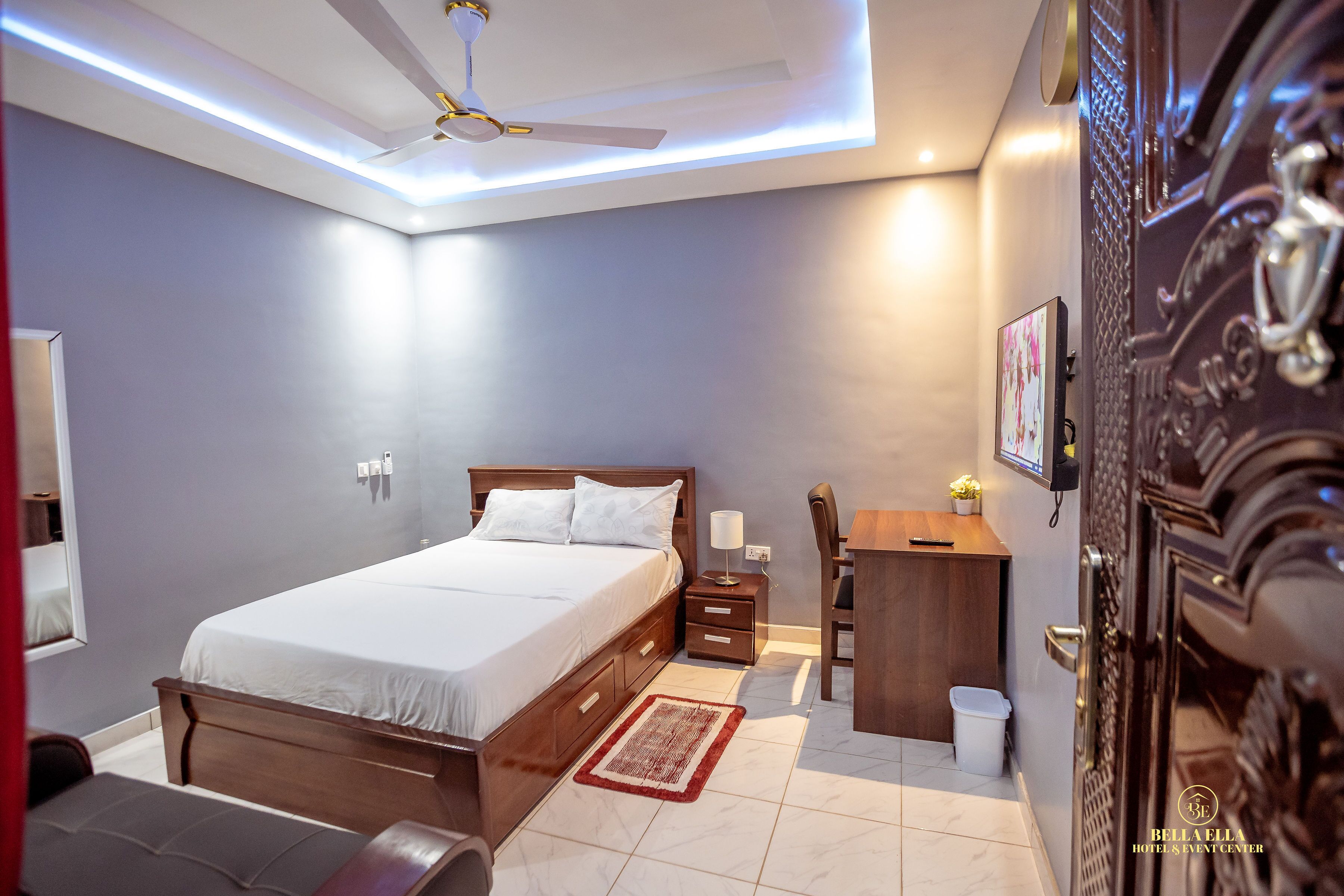Un dormitorio moderno con una cama, mesita de noche, lámpara y un escritorio pequeño con una silla.