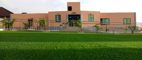 A modern building with a flat roof, a central entrance, and a staircase leading to the entrance.