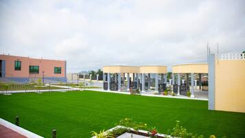 A modern building with a green lawn and a covered outdoor area with columns.