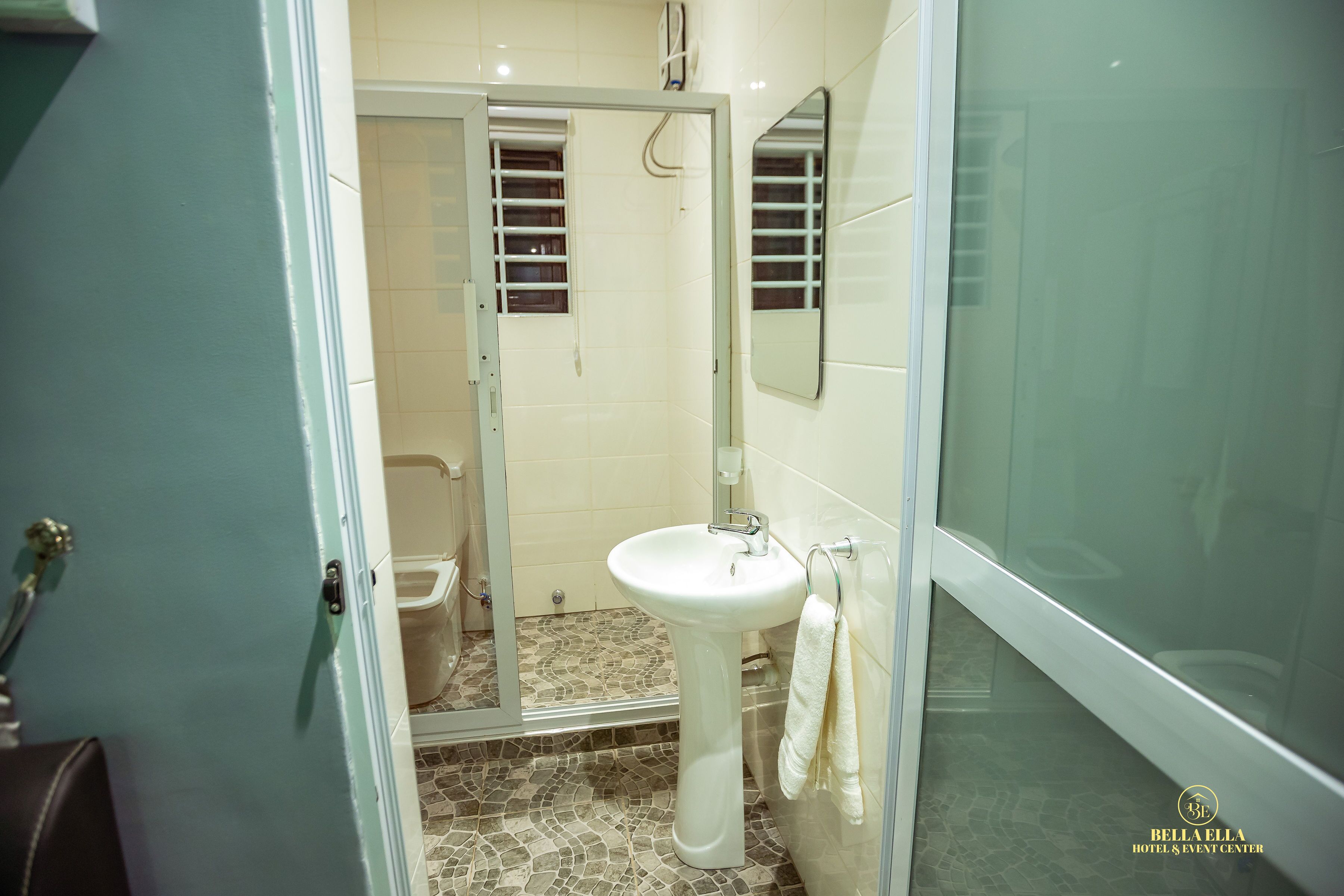 A bathroom with a glass shower enclosure, a pedestal sink, and a toilet.