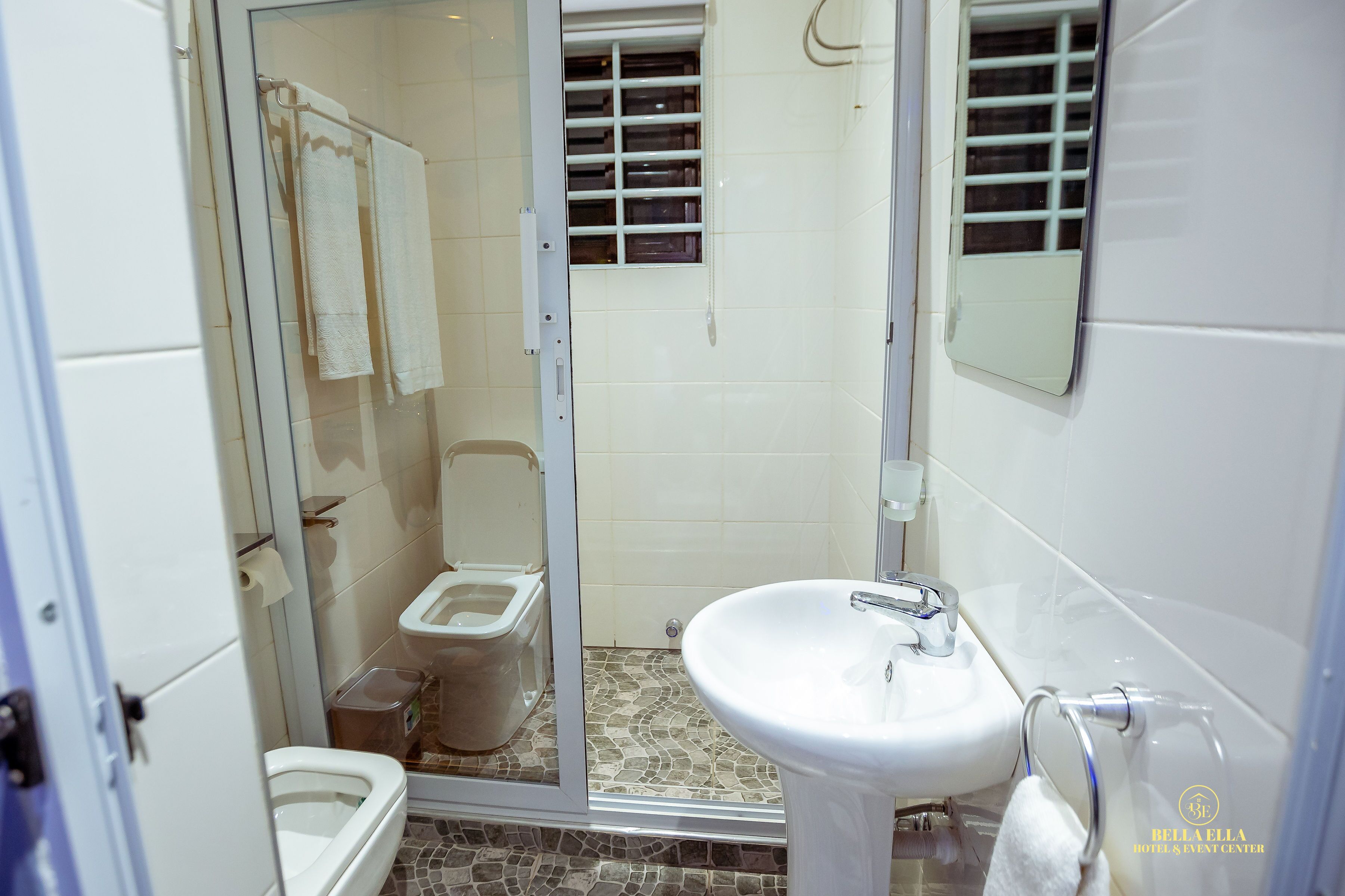 A bathroom with a glass shower enclosure, a toilet, and a sink.