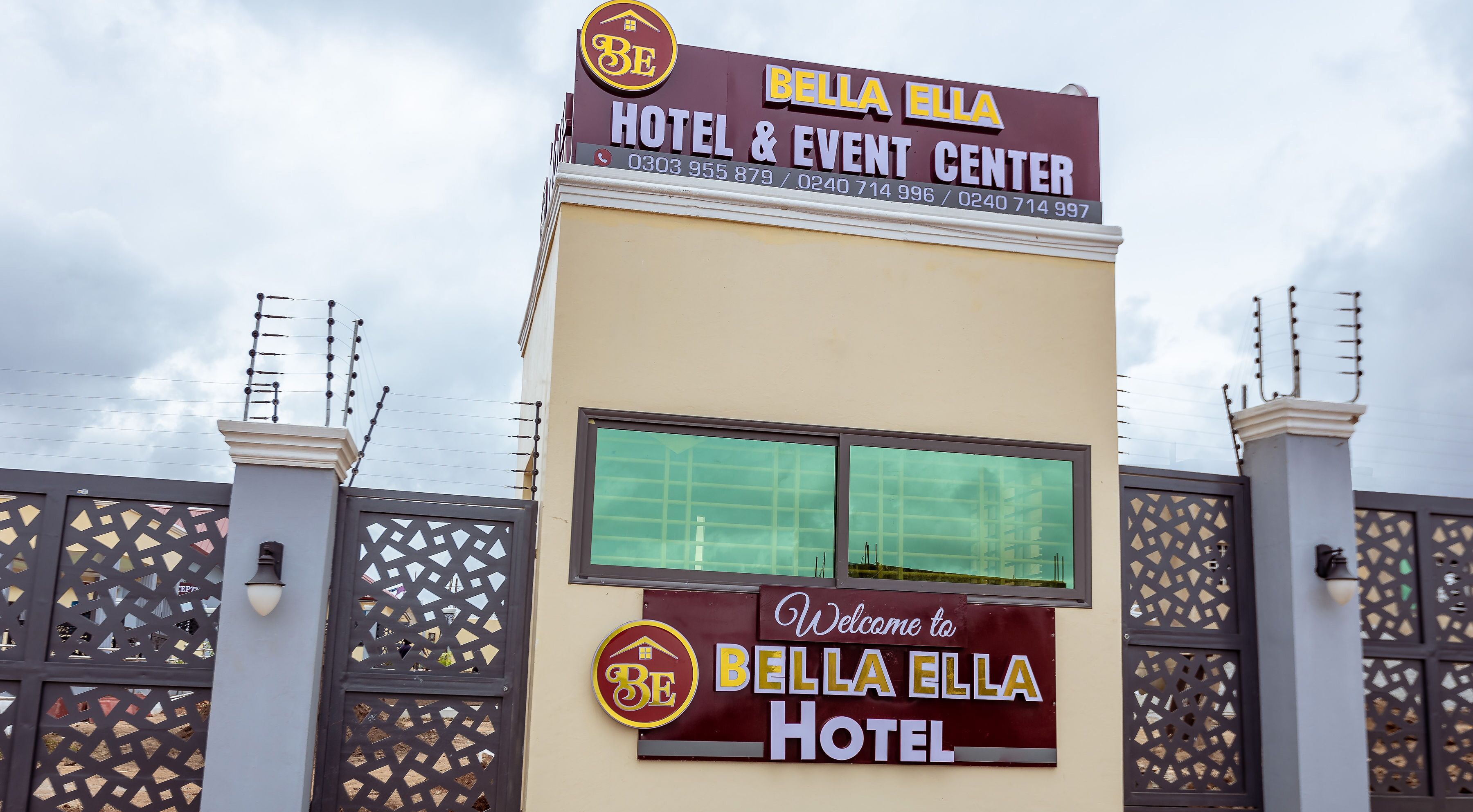 The exterior of Bella Bella Hotel & Event Center with a prominent sign and a decorative gate.