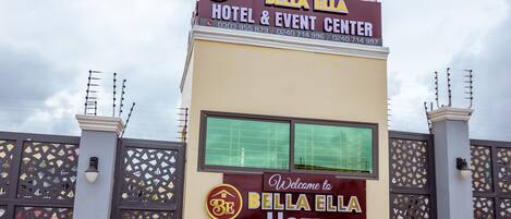 The exterior of Bella Bella Hotel & Event Center with a prominent sign and a decorative gate.
