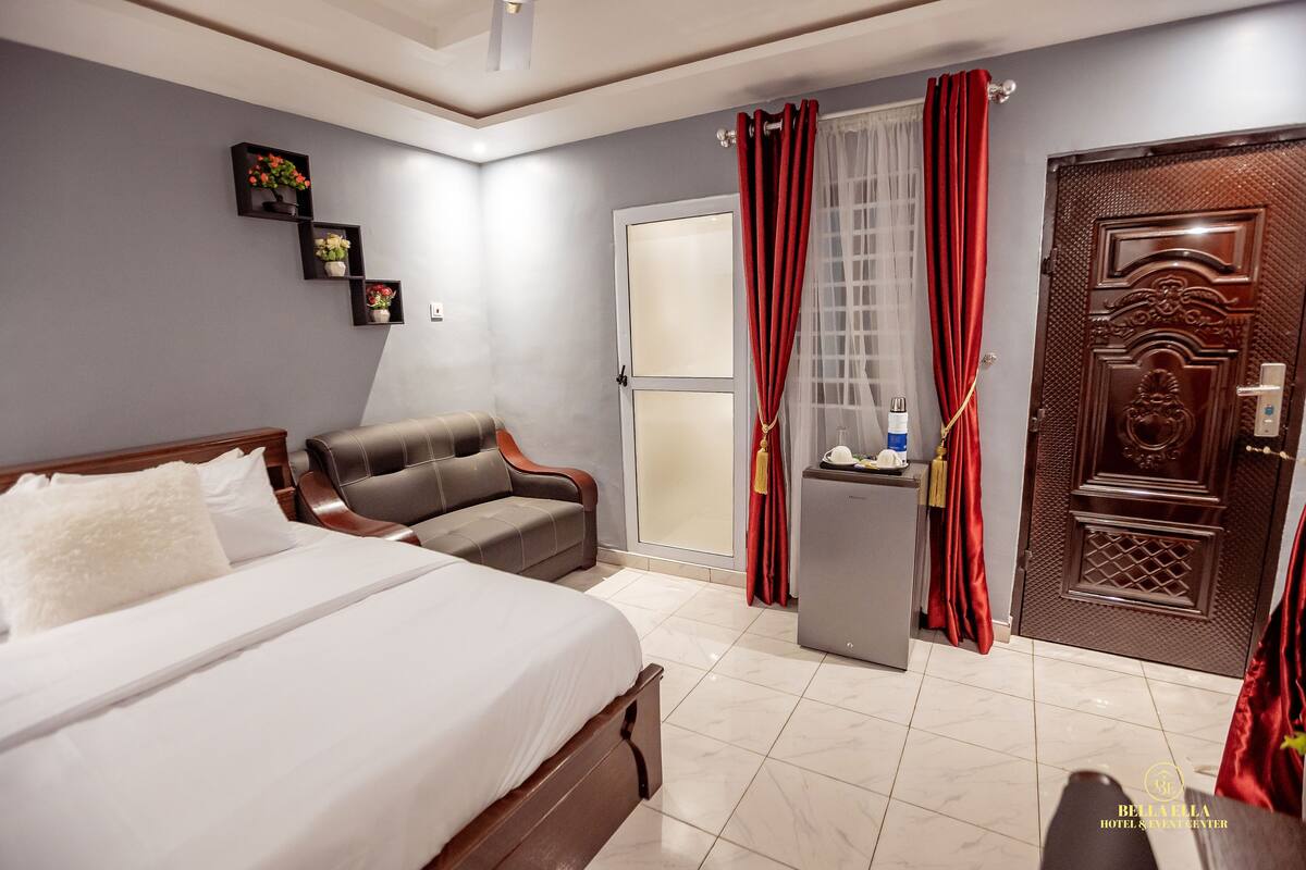 Ein Hotelzimmer mit einem Bett, einem Sofa, einem Schreibtisch und einer Tür.