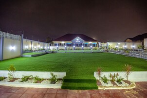 A hotel with a well-maintained lawn, a central building with a sign, and a gated entrance.