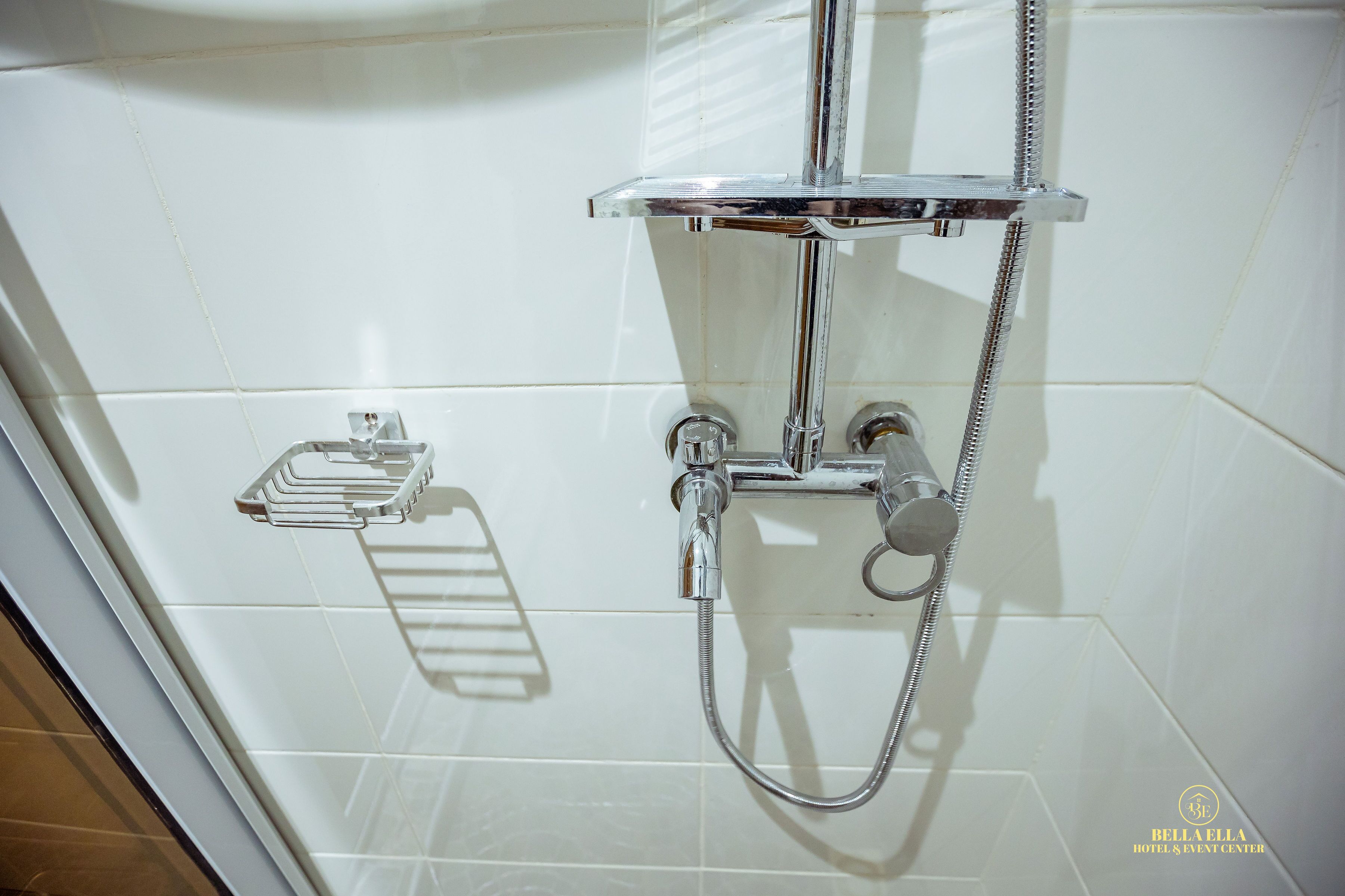 Een douche met chroombeslag en een glazen plank.