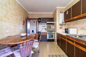 Uma cozinha compacta com uma mesa de jantar redonda, cadeiras, fogão, forno, micro-ondas e pia.