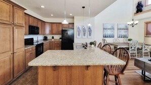 A modern kitchen with wooden cabinets, a granite island, and pendant lighting. - New! Peaceful Mountain Views, Deck, Trails nearby, Pool Table. (Mars Hill)