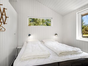 Un dormitorio con dos camas, una ventana con vistas y lámparas fijadas a la pared.
