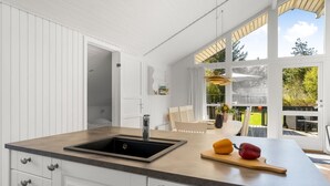 A kitchen with a sink, Bosch dishwasher, and a large window overlooking a garden.