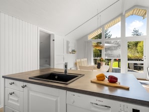 A kitchen with a sink, Bosch dishwasher, and a large window overlooking a garden.