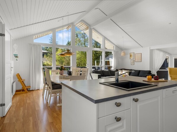 A modern kitchen with white cabinetry, a large island with a sink, and a dining area with chairs.