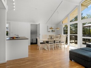 Una cocina moderna con zona de comedor, suelo de madera y ventanas amplias.