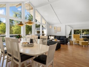 A spacious room with a dining table, chairs, a sofa, and a yellow armchair.