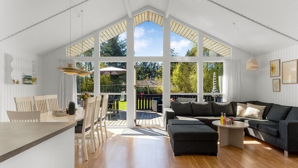 A spacious living area with a large window, a dining table with chairs, a sofa, and a small coffee table.
