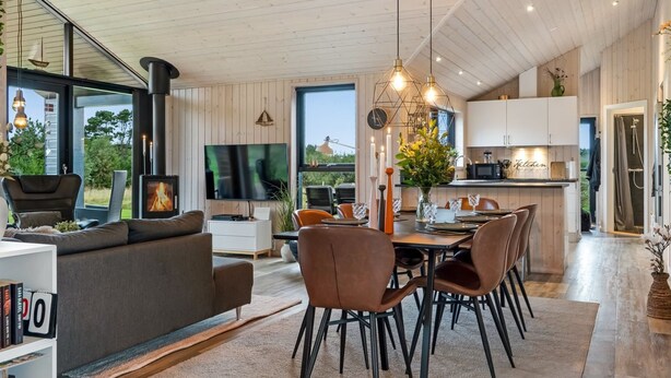 Un salon moderne avec une cheminée, un coin repas avec des chaises et une cuisine équipée de placards.
