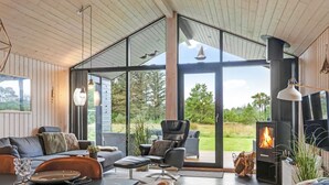 Un salon moderne doté d’une cheminée, de grandes fenêtres et offrant une vue sur l’extérieur.