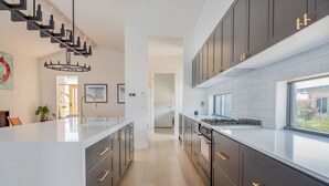 A modern kitchen with dark cabinetry, a central island, and a staircase leading to another level.