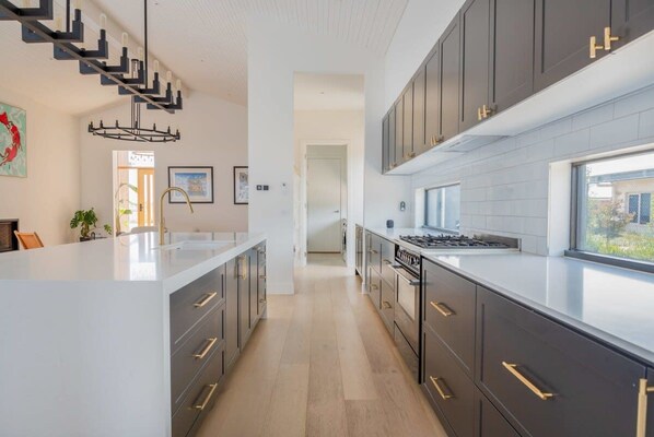 Une cuisine moderne avec des meubles de couleur sombre, un îlot central et un escalier menant à un autre niveau.