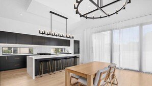 A modern kitchen with a central island, bar stools, and a dining table with chairs.