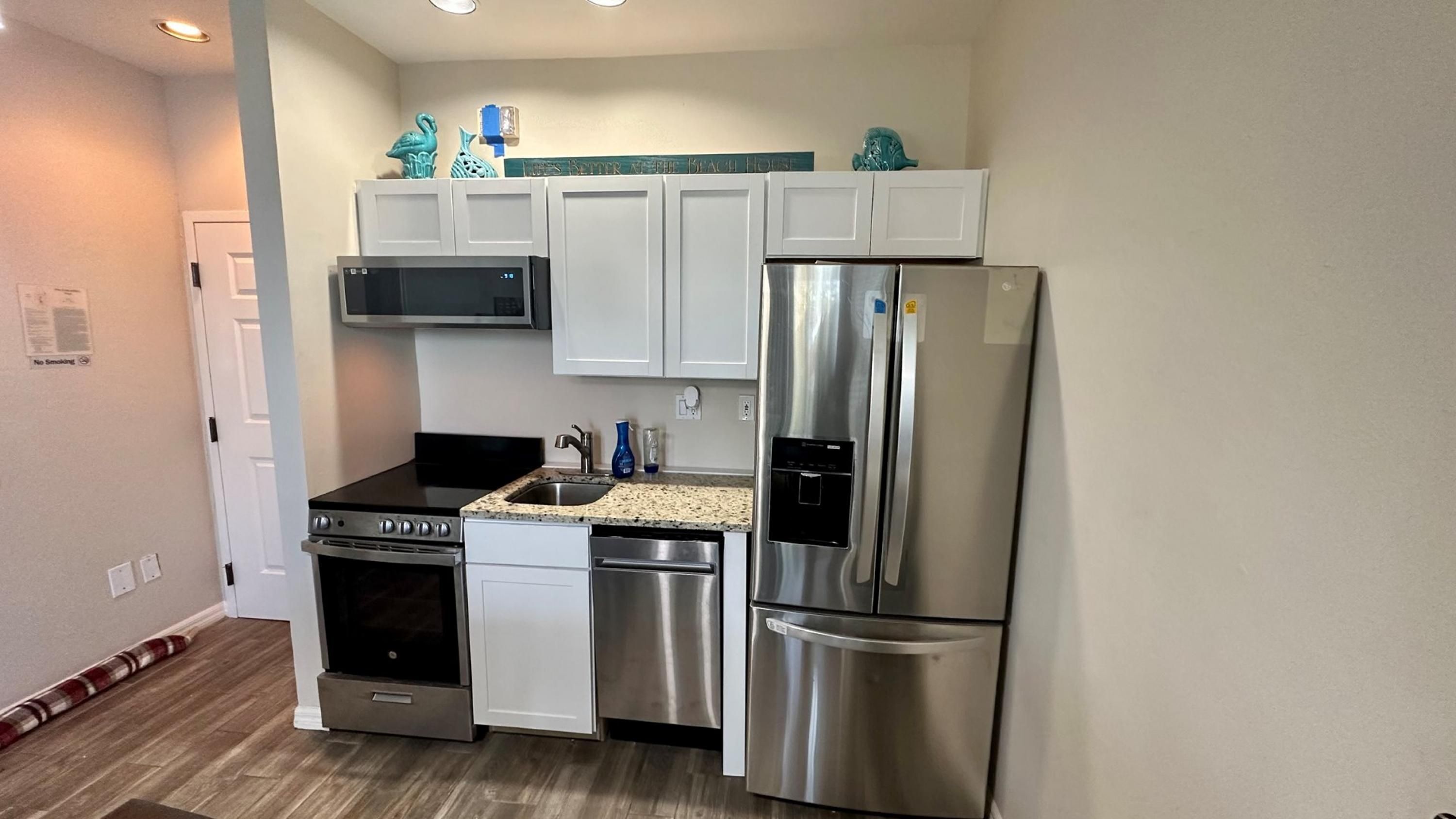 A compact kitchen with a stainless steel refrigerator, microwave, stove, and dishwasher.