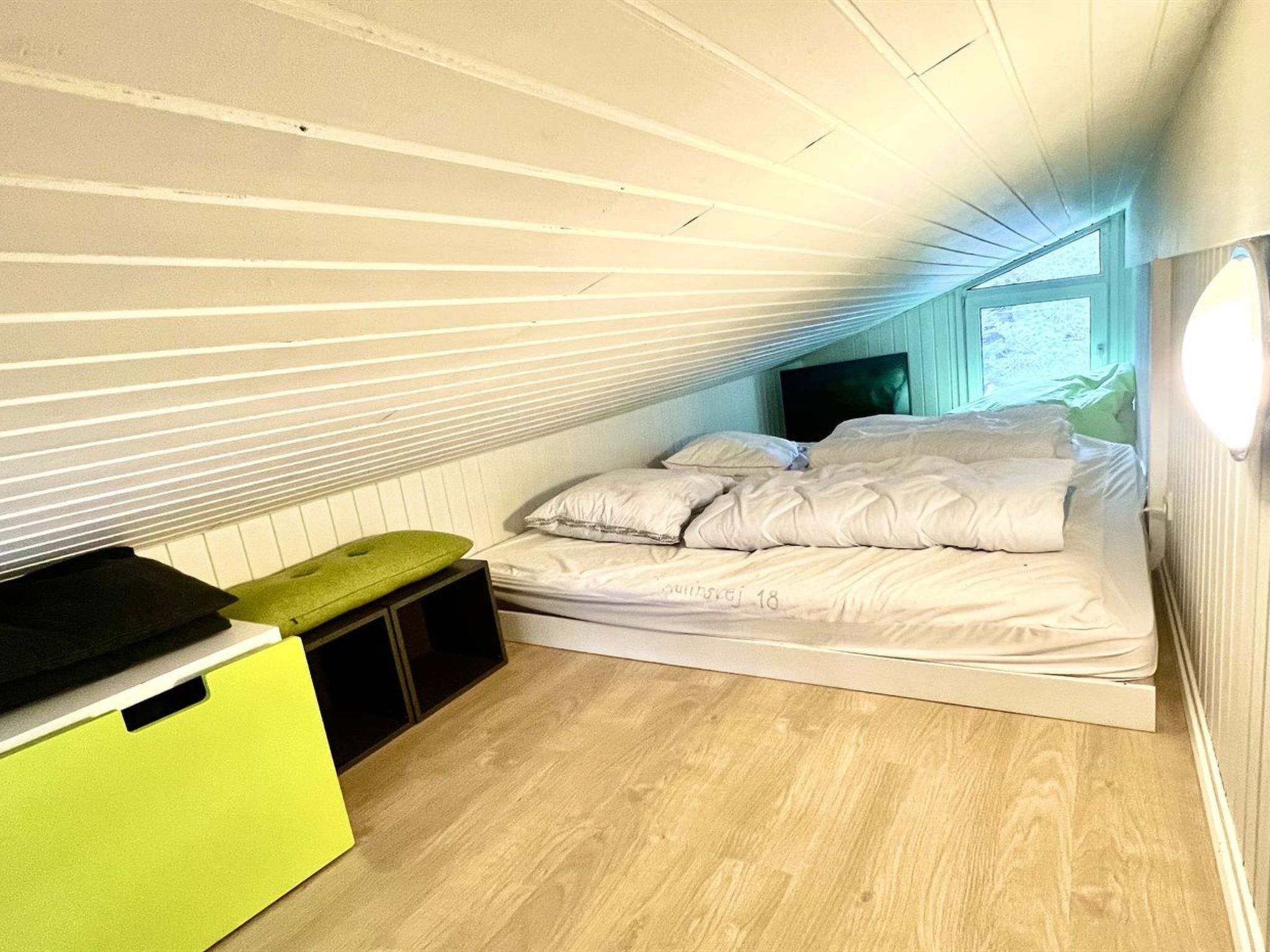 Een slaapkamer met een bed, een groene kast en een raam.