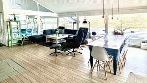 Un salón amplio con piso de madera, una gran mesa de comedor y muebles modernos.