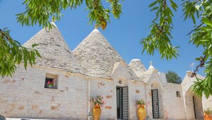 A stone building with conical roofs, a small window with flowers, and a door. - TD Trulli Della Magnolia Trulli w Amazing Garden (Monopoli)