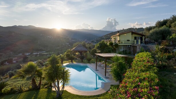 A pool with a pergola, surrounded by lush greenery and a view of distant hills. - Villa Vittorio 6 2 Emma Villas (Imperia)