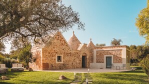 A stone building with a central door and multiple conical roofs. - Trulli Biancapetra 8 2 Emma Villas (Francavilla Fontana)
