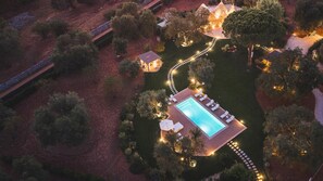 An aerial view of a property with a swimming pool, lounge chairs, and a well-lit pathway. - Trulli Biancapetra 8 2 Emma Villas (Francavilla Fontana)