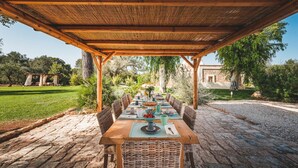 An outdoor dining area with a pergola, stone flooring, and a view of a stone building. - Trulli Biancapetra 8 2 Emma Villas (Francavilla Fontana)