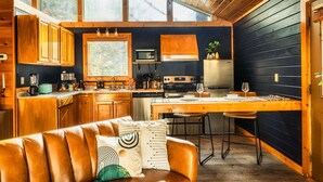 Uma cozinha moderna com armários de madeira, uma ilha central e uma área de refeições com mesa e cadeiras de madeira.