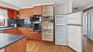 Een moderne keuken met houten kastjes, een inbouwoven, een magnetron en een witte koelkast.
