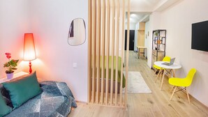 A modern living room with a sofa, a table with a laptop, and a dining area with yellow chairs. - H&B apartments Akhmeta (Tbilisi)