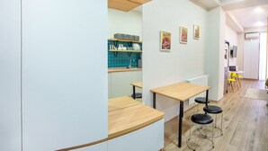 A modern kitchen with white cabinetry, a wooden countertop, and a blue backsplash. There are two stools and a small table. - H&B apartments Akhmeta (Tbilisi)