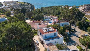 A coastal residential area with houses, a swimming pool, and a view of the sea.