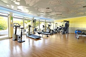 A gym with cardio machines, weight equipment, and large windows.