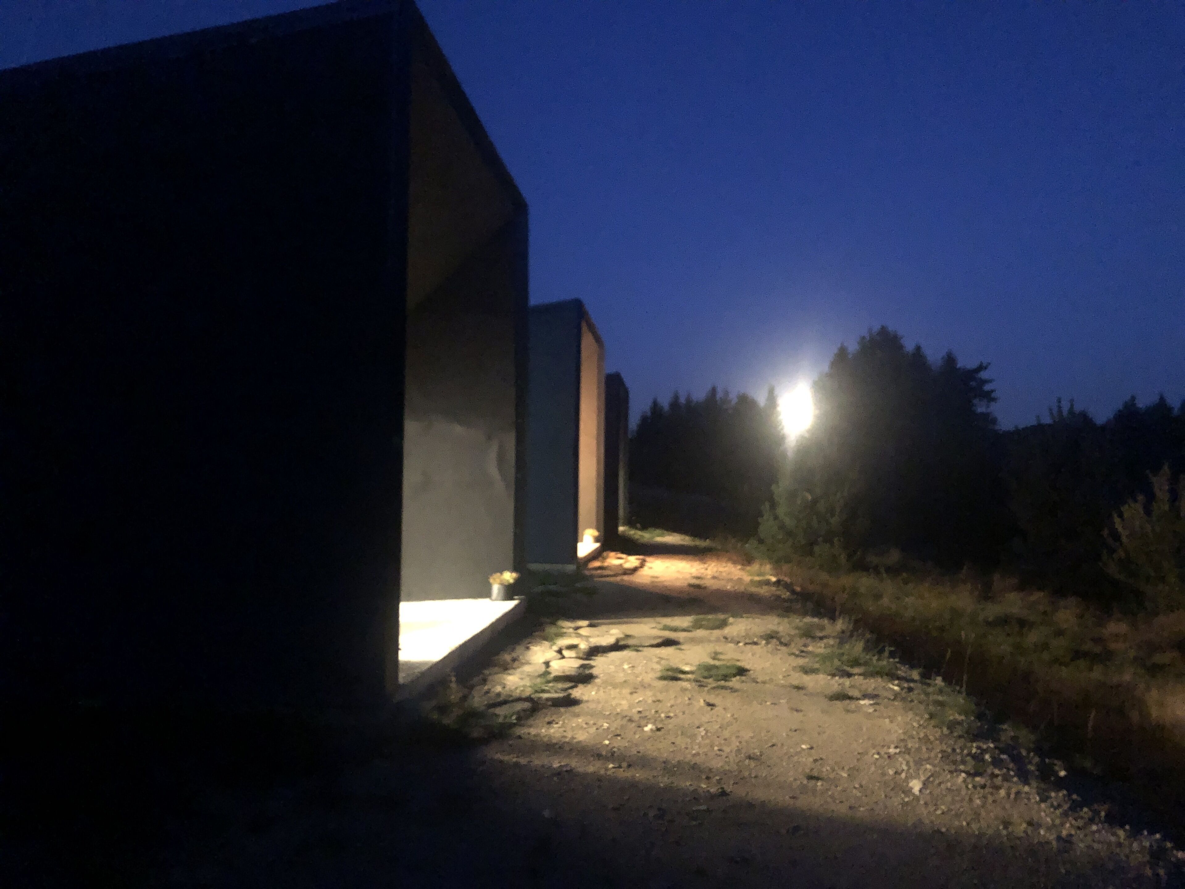 Een gebouw met een betonnen gevel en een verhard pad dat naar een deur leidt.