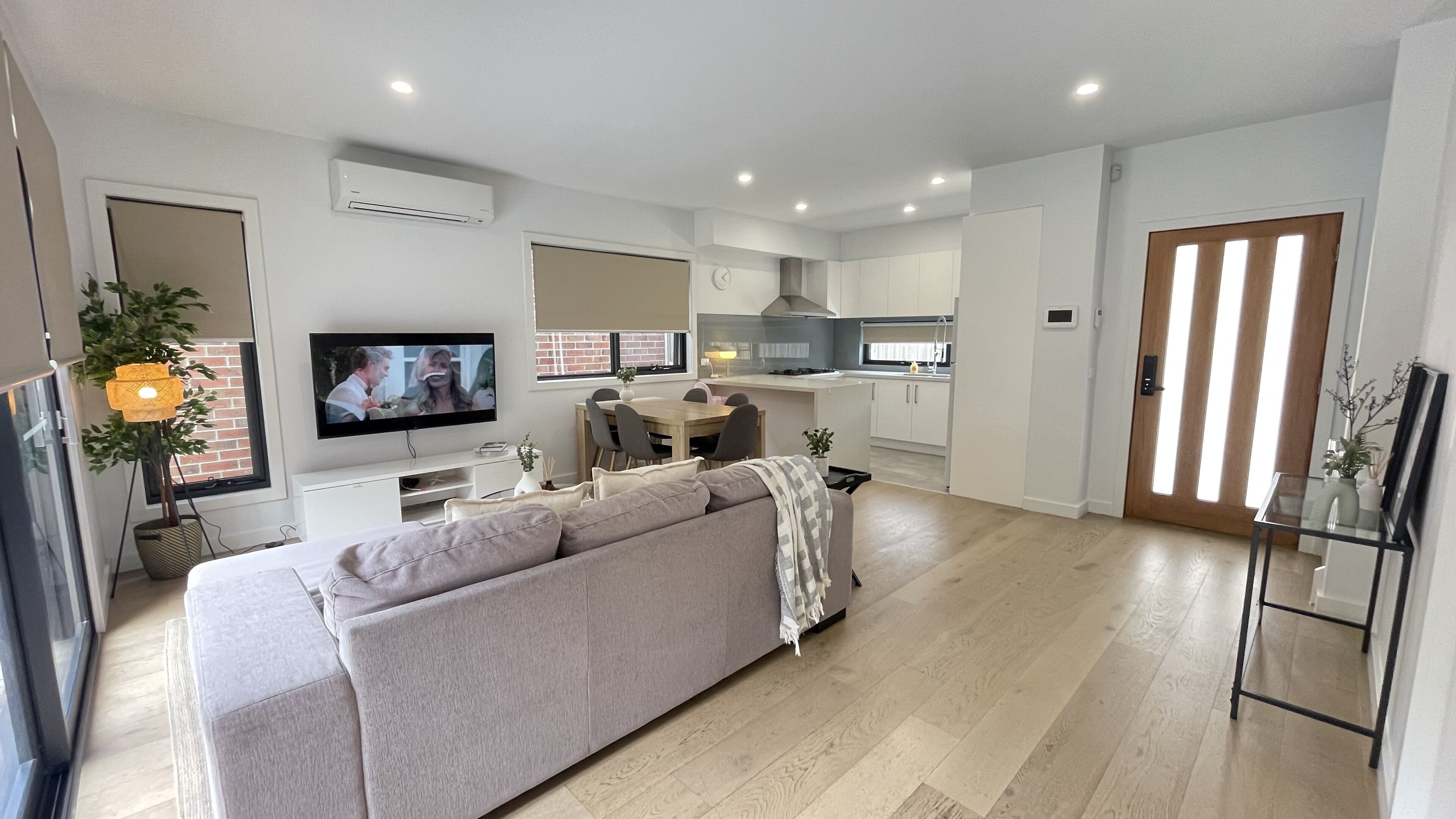 A modern living room with a sofa, TV, and dining area.