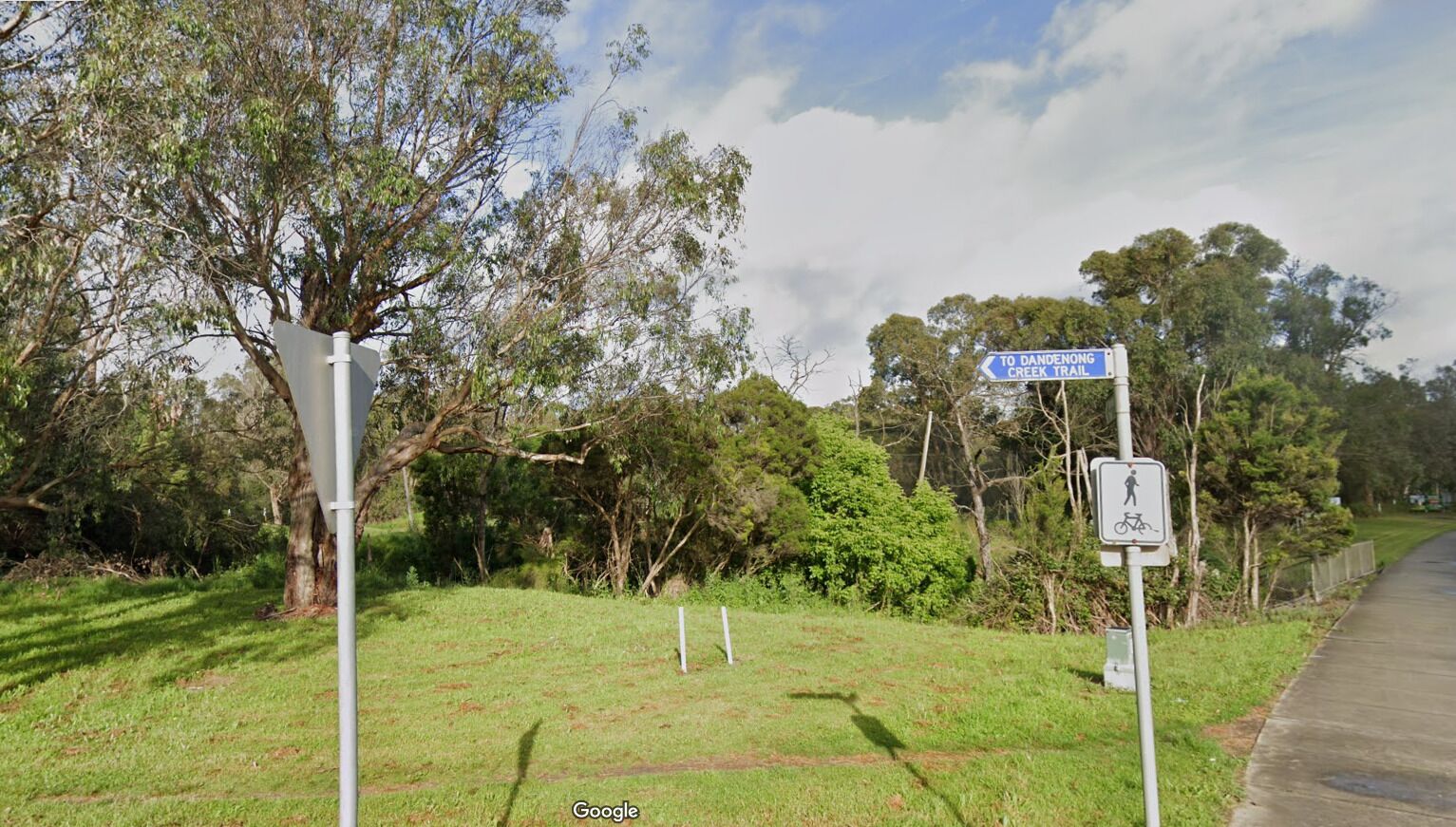 A signpost with directions to Dandenong Creek Trail and a pedestrian/bicycle symbol.